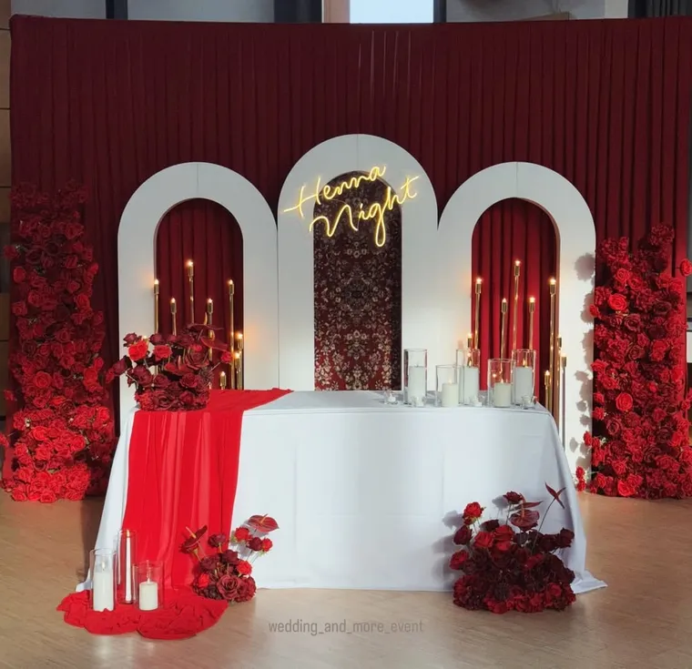 Hennaabend-Dekoration mit roten Blumen und weißer Tischdecke