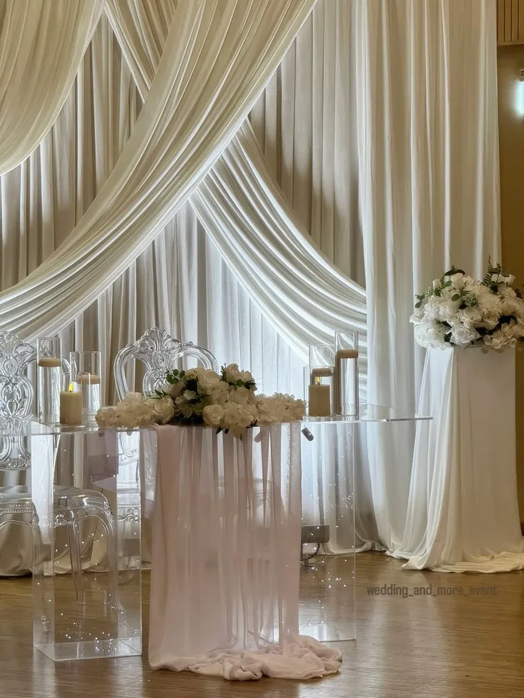 Hochzeitsbühne mit weißer Draperie und Brautpaartisch