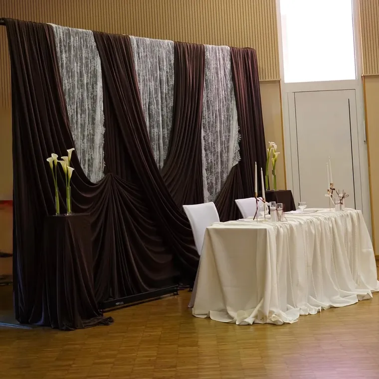 Hintergrund in Dunkelbraun mit Spitze und Brautpaartisch im Saal