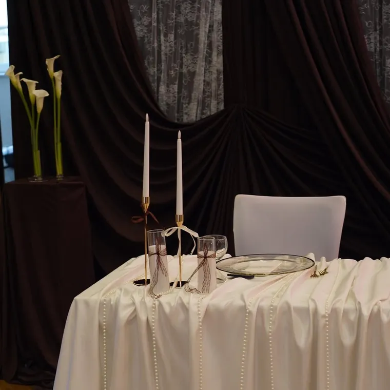 Brautpaartisch vor dunkelbrauner Draperie mit Calla und Kerzen