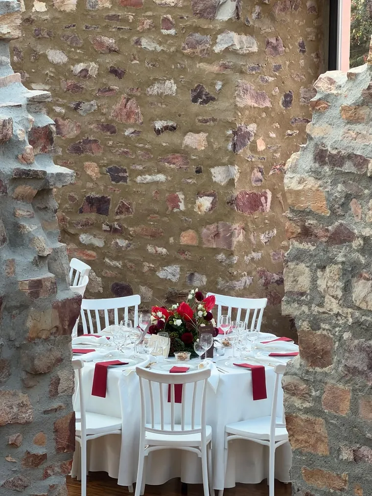 Runder Festtisch in Weiß und Bordeaux vor historischer Steinwand