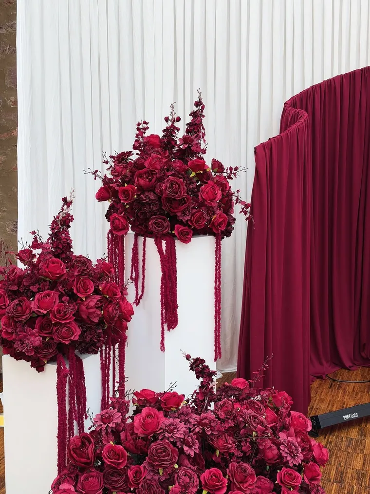 Bordeauxrote Rosen und Amarant auf weißen Podesten